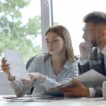 Dos empresarios discutiendo sobre documentos financieros en una oficina, ilustrando el delito de administración desleal