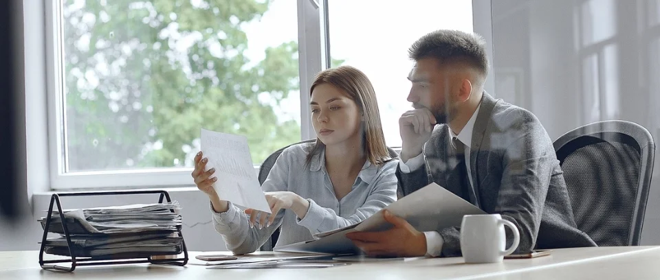 Dos empresarios discutiendo sobre documentos financieros en una oficina, ilustrando el delito de administración desleal