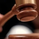 Mazo de juez sobre los artículos del Código Penal que regulan el delito de allanamiento de morada.